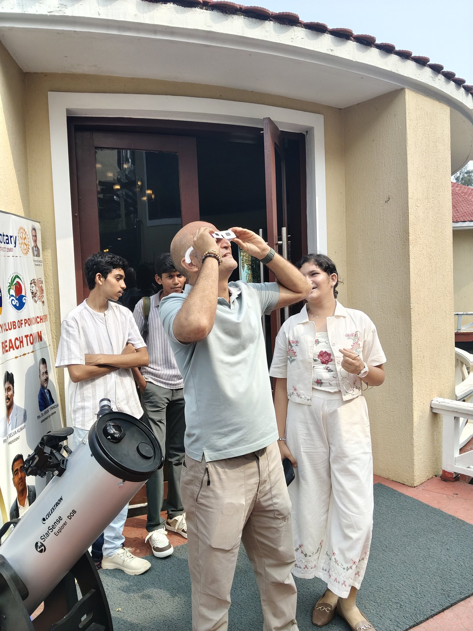 Visitors gathered around a telescope at an outdoor astronomy event.